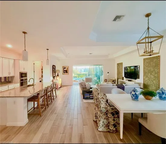 Dining area featuring a tray ceiling, light wood-style flooring, ornamental molding, and a chandelier