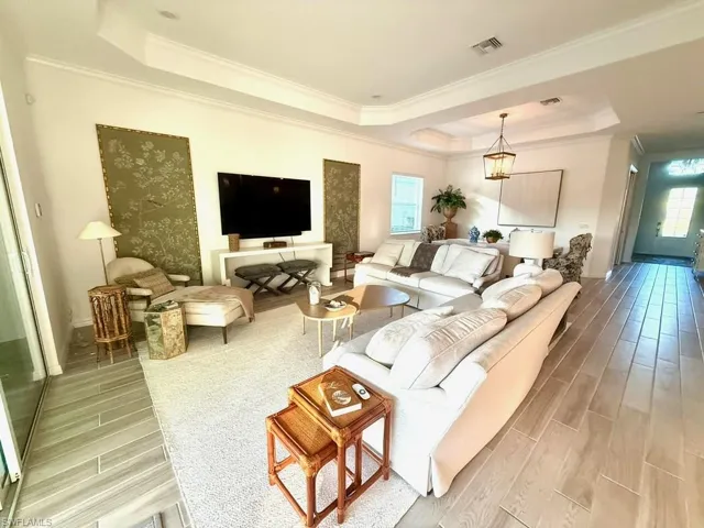 Living area featuring a raised ceiling, wood tiled floors, and crown molding