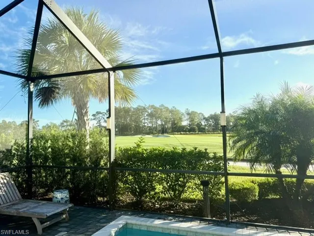 View of swimming pool featuring glass enclosure, a sunroom, view of golf course, and view of wooded area