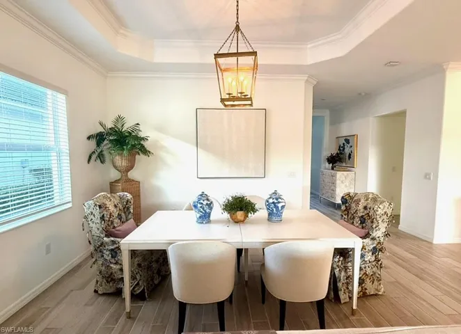 Dining space with a tray ceiling, ornamental molding, and wood finished floors