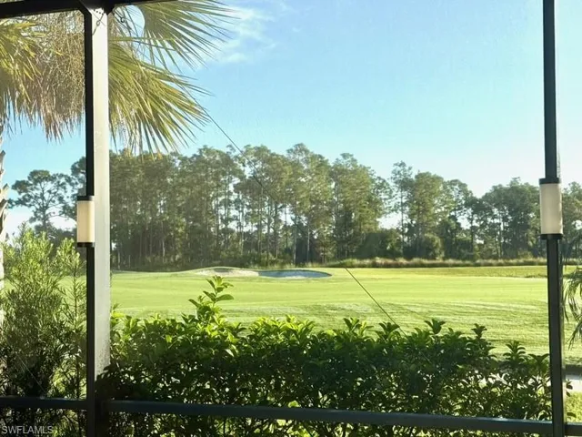 View of home's community featuring golf course view, a lawn, and view of wooded area