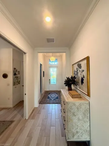 Hallway featuring crown molding and light wood-style flooring