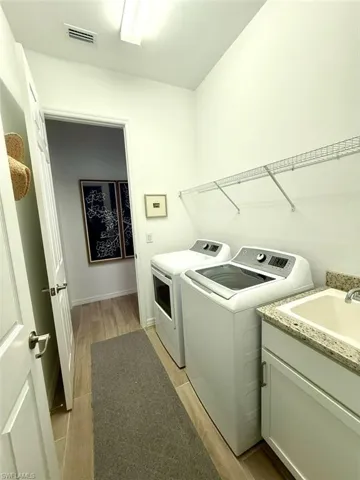 Laundry area with light wood finished floors and washer and clothes dryer