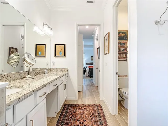 Bathroom featuring light wood finished floors, double vanity, and ornamental molding