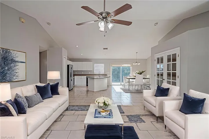 Living area with a ceiling fan, vaulted ceiling, french doors, and light tile patterned floors