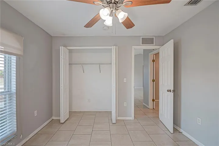Unfurnished bedroom featuring a ceiling fan, a closet, and light tile patterned floors
