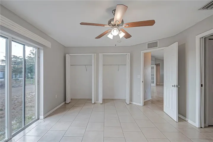 Unfurnished bedroom with two closets and a ceiling fan