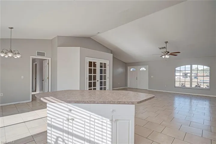 Kitchen featuring white cabinetry, light countertops, a ceiling fan, hanging lights, and open floor plan