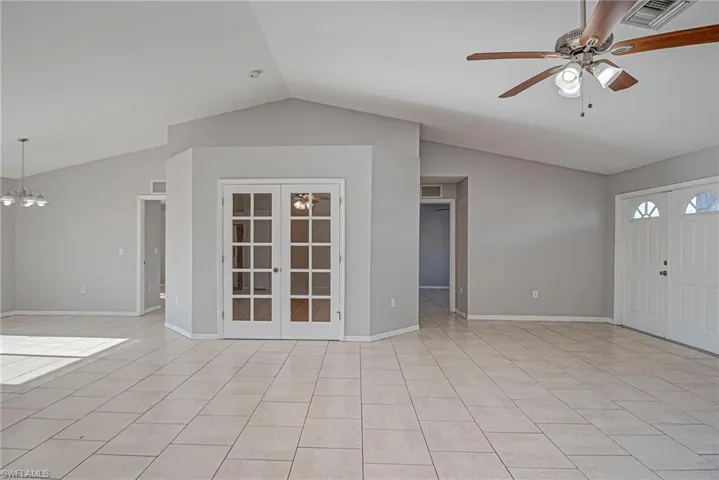 Foyer entrance with a ceiling fan, french doors, a chandelier, and light tile patterned floors