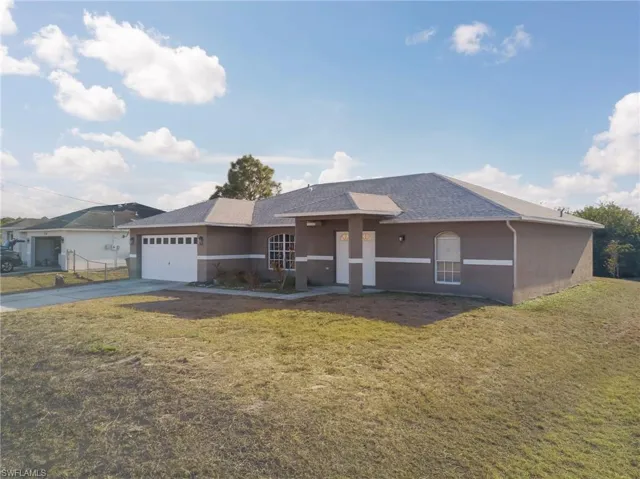 Single story home featuring a front yard, stucco siding, driveway, an attached garage, and roof with shingles