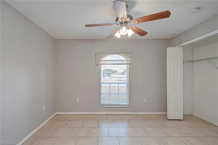 Unfurnished bedroom with a closet, ceiling fan, and light tile patterned flooring