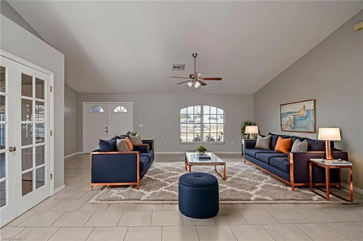 Living area featuring lofted ceiling, a ceiling fan, and french doors