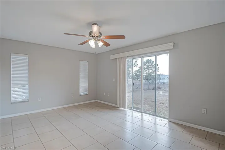 Empty room with a ceiling fan and light tile patterned flooring