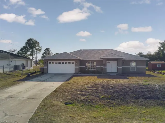 Ranch-style home featuring concrete driveway, stucco siding, a front lawn, and a garage