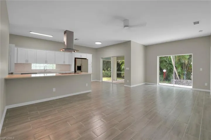 Unfurnished living room featuring ceiling fan, light hardwood / wood-style flooring, sink, and plenty of natural light