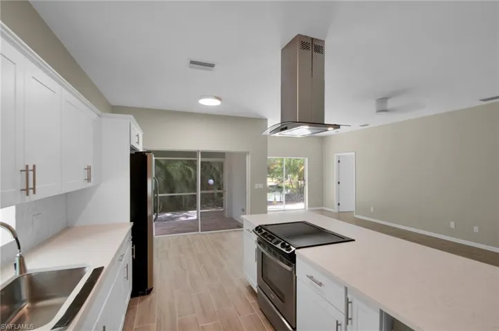 Kitchen with white cabinets, sink, appliances with stainless steel finishes, and island exhaust hood