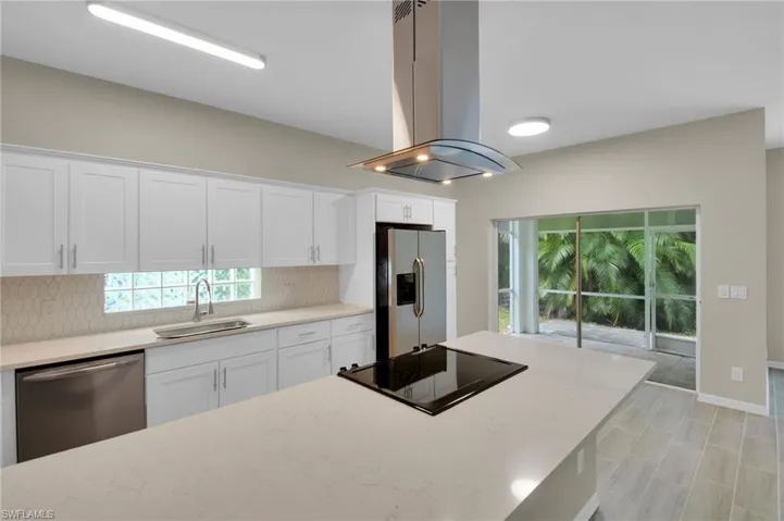 Kitchen with white cabinetry, tasteful backsplash, sink, appliances with stainless steel finishes, and island range hood