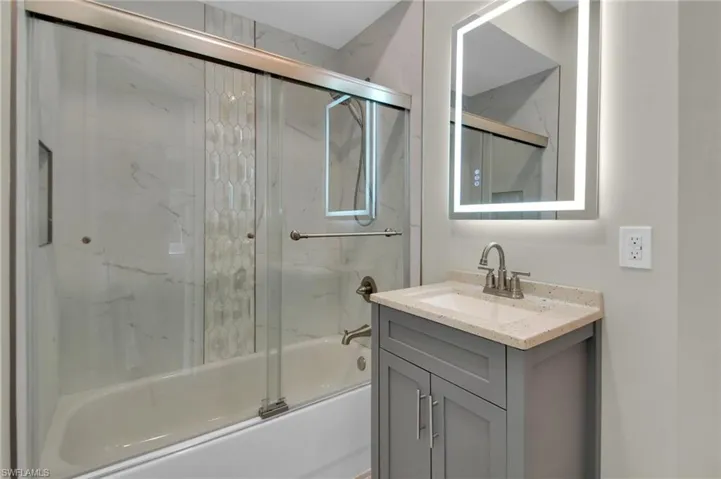 Bathroom with vanity and enclosed tub / shower combo