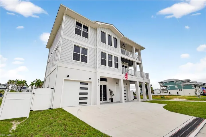 View of front of property with an attached garage, a gate, concrete driveway, and a balcony