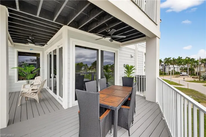 Wooden terrace with a ceiling fan and outdoor dining area - Virtually Edited Image