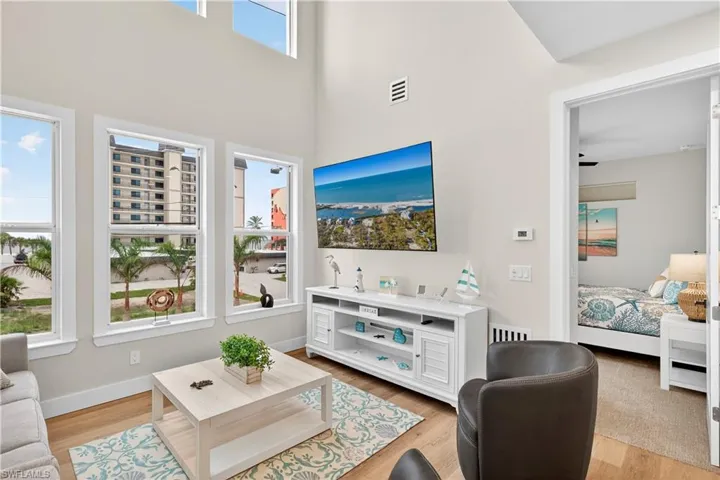 Living area featuring light wood-style floors and a high ceiling - Virtually Edited Image