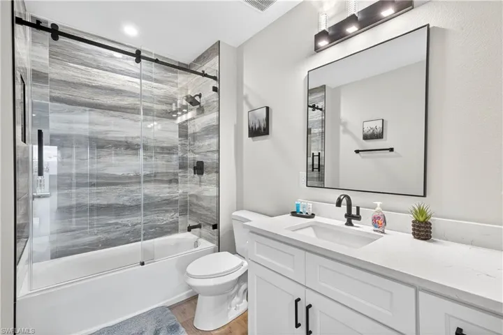 Full bathroom with vanity, shower / bath combination with glass door, and light wood-style flooring - Virtually Edited Image