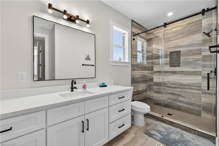 Bathroom featuring vanity, a shower stall, and light wood-style flooring - Virtually Edited Image