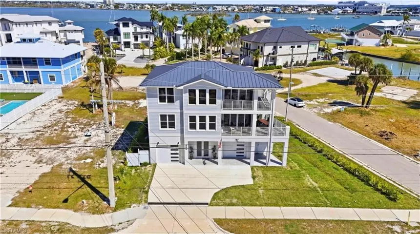 View of front of property featuring a water view, a residential view, a balcony, and a front lawn - Virtually Edited Image