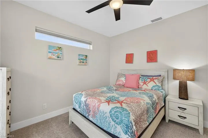 Carpeted bedroom featuring a ceiling fan and baseboards - Virtually Edited Image
