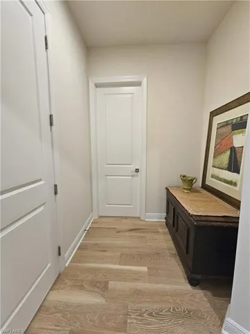 Hallway featuring light wood-type flooring and baseboards