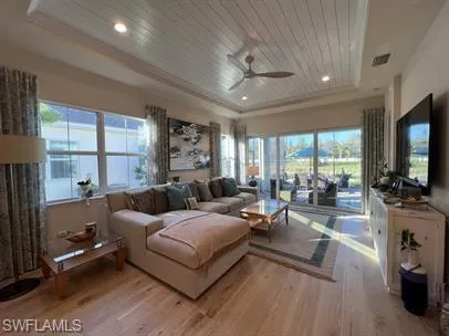 Living room with wooden ceiling, a ceiling fan, light wood finished floors, a raised ceiling, and recessed lighting