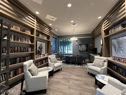 Living area featuring wood finished floors, crown molding, and recessed lighting