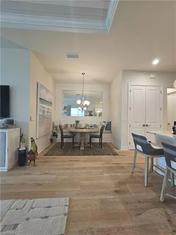 Dining space with light wood-type flooring, a chandelier, recessed lighting, and crown molding
