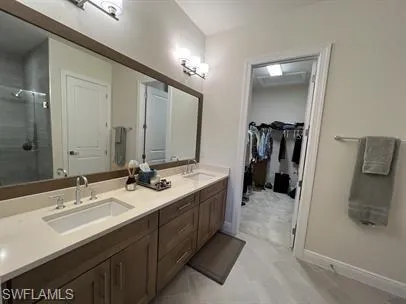 Bathroom with double vanity, a shower stall, and a walk in closet