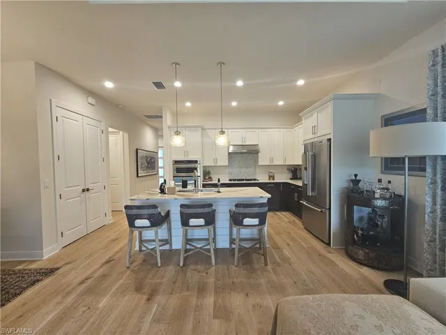 Kitchen with white cabinets, a kitchen breakfast bar, recessed lighting, pendant lighting, and stainless steel appliances