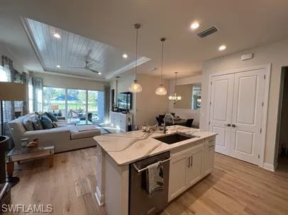 Kitchen featuring open floor plan, light wood finished floors, a center island with sink, pendant lighting, and recessed lighting