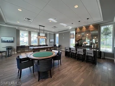 Recreation room with ornamental molding, plenty of natural light, wood finished floors, and recessed lighting