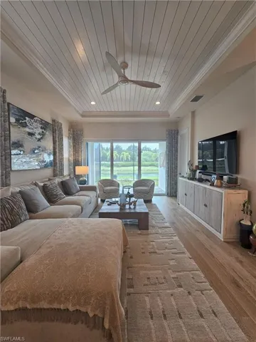 Bedroom with wooden ceiling, light wood finished floors, a tray ceiling, and access to outside