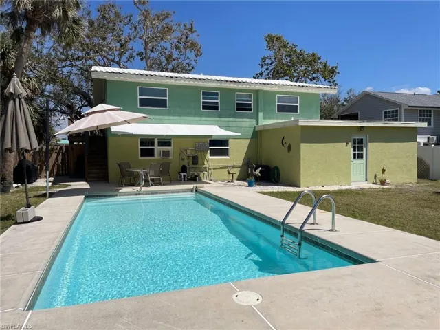 Rear view of house with remote shade awning, and outdoor patio, all fenced