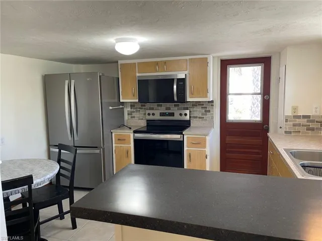 Kitchen with backsplash, Newappliances with stainless steel finishes, a textured ceiling, and a sink