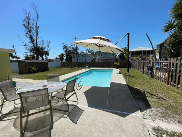 View of swimming pool with outdoor dining space, a patio, a fenced backyard, a storage unit, and a lawn