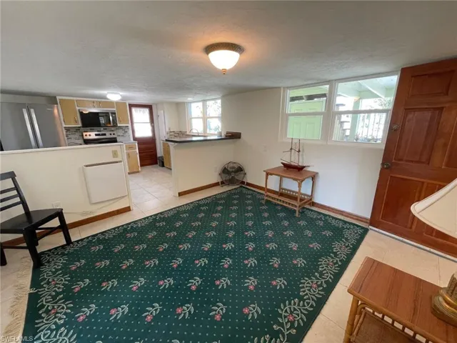 Sitting room featuring light tile patterned floors, a textured ceiling, and baseboards