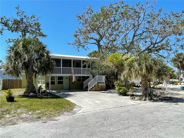 View of front of property featuring concrete driveway, fence, a screened Lanai and shady oak trees