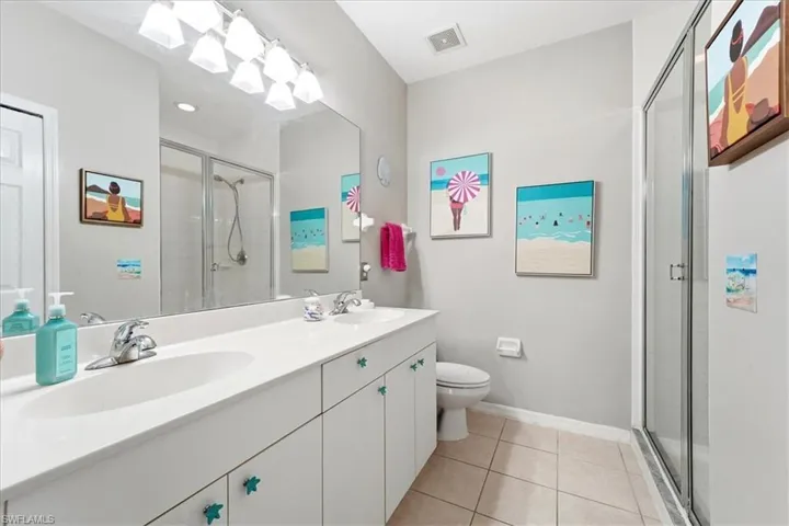 Bathroom featuring double vanity, a shower stall, and light tile patterned flooring