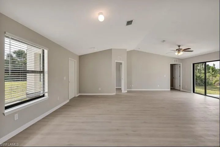 Empty room featuring light wood-type flooring, vaulted ceiling, and ceiling fan
