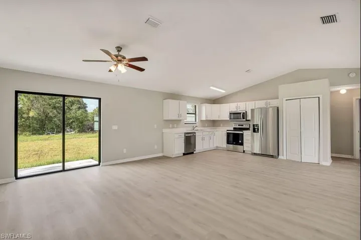 Unfurnished living room with ceiling fan, plenty of natural light, light hardwood / wood-style flooring, and lofted ceiling