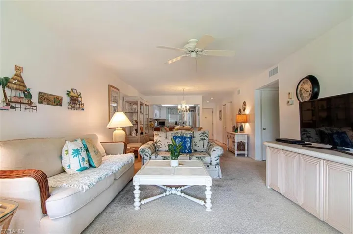 Living area with light colored carpet, a ceiling fan, and hanging lights