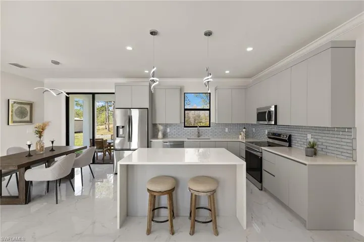 Kitchen featuring a kitchen breakfast bar, marble finish floor, a sink, modern cabinets, and appliances with stainless steel finishes