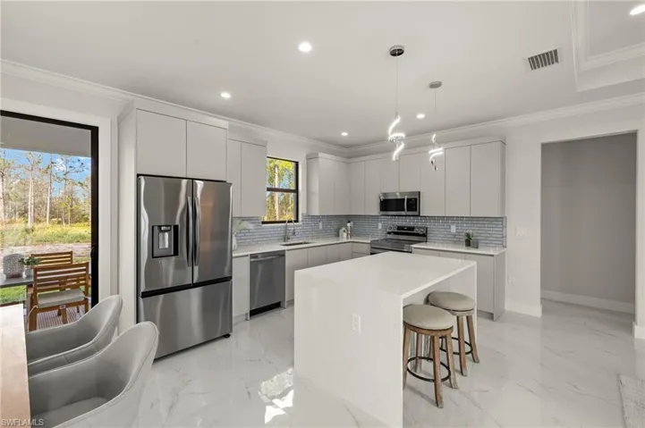 Kitchen with marble finish floor, a sink, crown molding, and appliances with stainless steel finishes