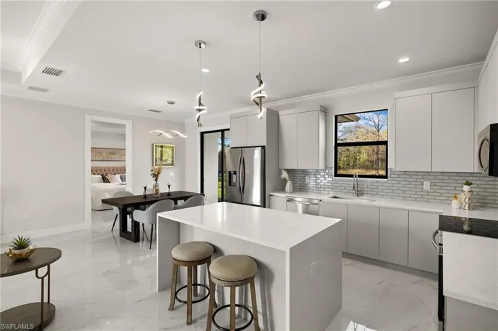 Kitchen featuring marble finish floor, a sink, modern cabinets, and appliances with stainless steel finishes
